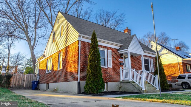 view of front facade with brick siding, fence, and a chimney