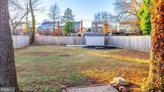 view of yard with a fenced backyard, an outdoor structure, and a storage shed