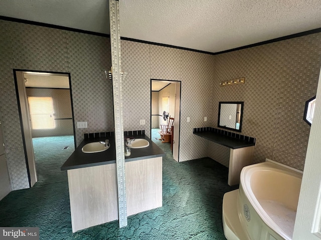 bathroom with ornamental molding, a tub, vanity, and a textured ceiling