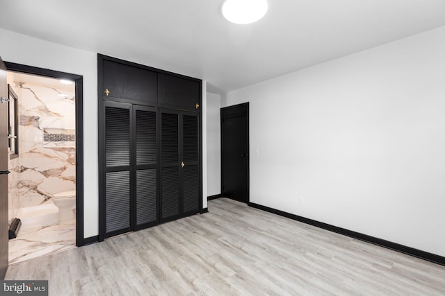 unfurnished bedroom featuring ensuite bath, light hardwood / wood-style floors, and a closet