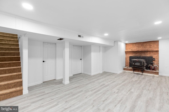 basement featuring a wood stove and light wood-type flooring