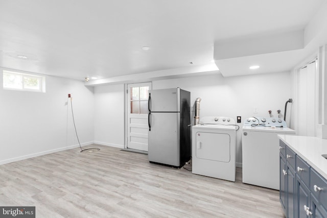 washroom with washer and clothes dryer and light hardwood / wood-style flooring