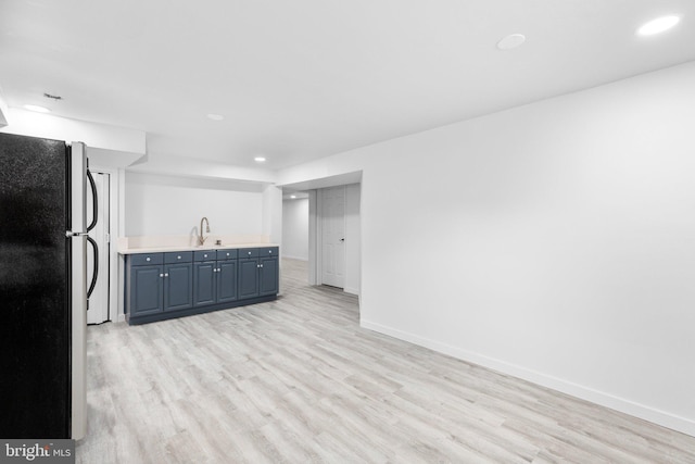 kitchen featuring blue cabinets, sink, stainless steel refrigerator, and light hardwood / wood-style floors