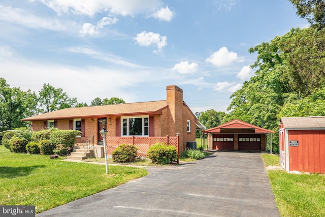 view of front of home with a carport, central AC, a front lawn, and a storage shed