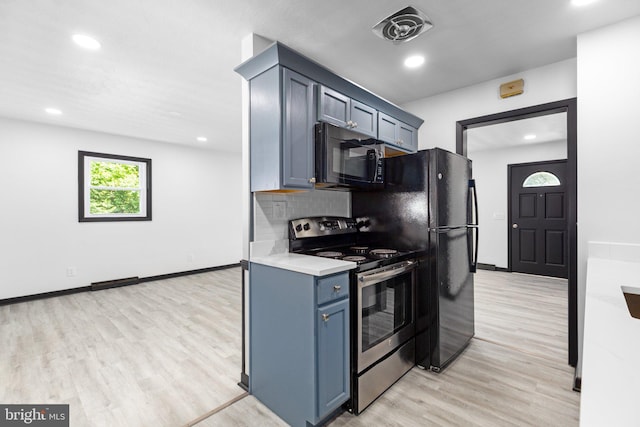 kitchen with electric stove, blue cabinets, and light wood-type flooring