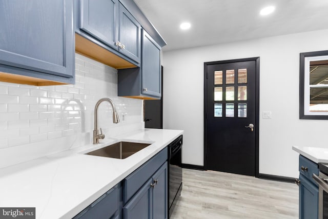 kitchen with tasteful backsplash, sink, black dishwasher, and blue cabinets