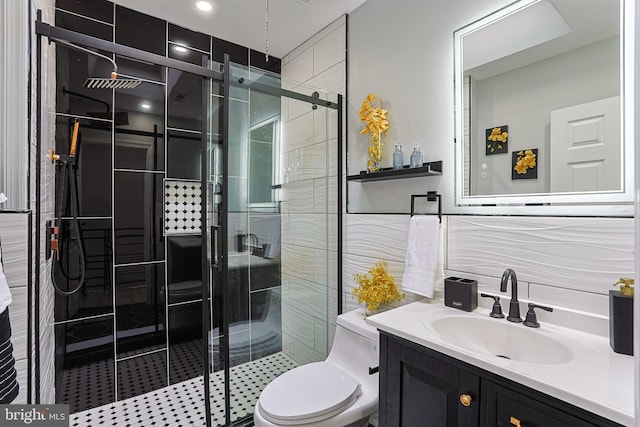 bathroom with vanity, toilet, a shower with door, and tile walls