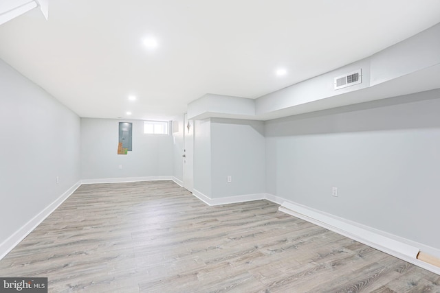 basement featuring electric panel and light hardwood / wood-style floors