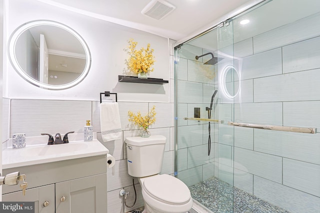 bathroom featuring vanity, a shower with shower door, tile walls, and toilet