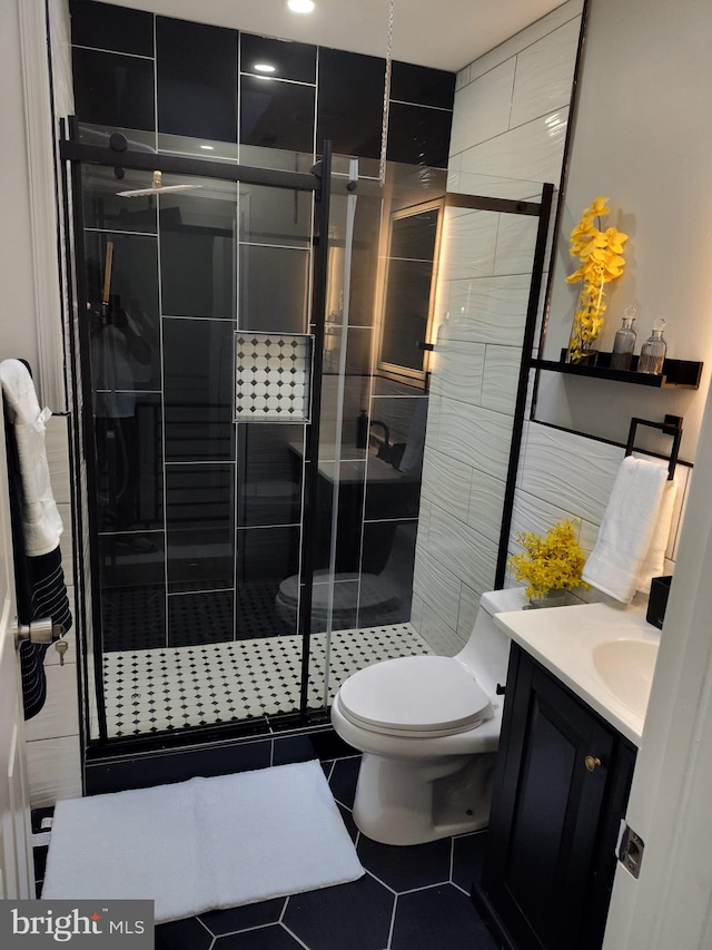 bathroom with tile patterned flooring, vanity, a shower with shower door, and toilet