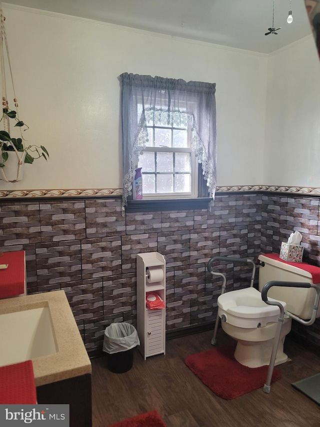 bathroom featuring crown molding, tile walls, hardwood / wood-style floors, vanity, and toilet