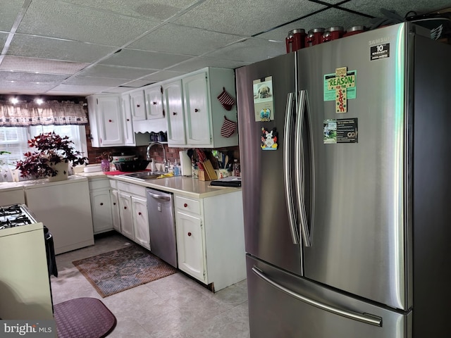 kitchen featuring sink, a paneled ceiling, stainless steel appliances, white cabinets, and washer / clothes dryer