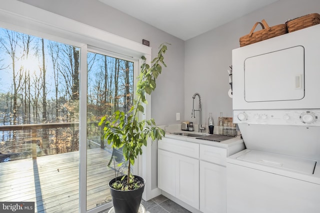 clothes washing area featuring sink, cabinets, stacked washer and clothes dryer, and light tile patterned flooring