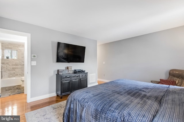 bedroom featuring ensuite bath and wood-type flooring