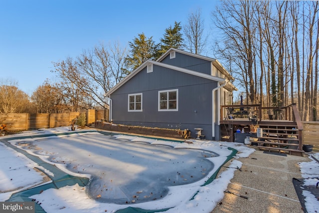 snow covered back of property featuring a wooden deck