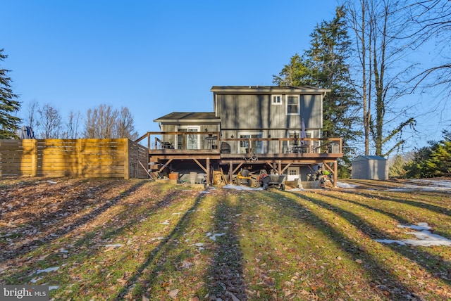 back of house featuring a wooden deck, a storage shed, and a lawn