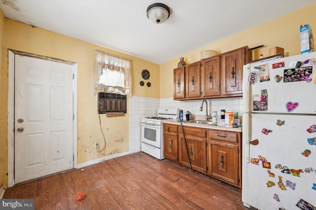 kitchen with hardwood / wood-style floors, white appliances, sink, and a wall mounted AC