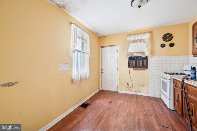 kitchen featuring white gas range oven, hardwood / wood-style floors, and tile walls