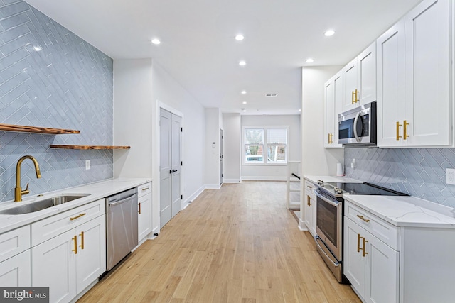 kitchen with appliances with stainless steel finishes, light stone countertops, sink, and white cabinets