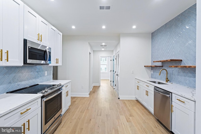 kitchen with light stone countertops, white cabinetry, appliances with stainless steel finishes, and sink