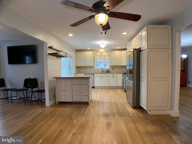 kitchen featuring sink, white cabinetry, tasteful backsplash, stainless steel appliances, and light hardwood / wood-style floors