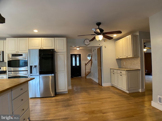 kitchen featuring light hardwood / wood-style flooring, ceiling fan, white cabinetry, backsplash, and stainless steel appliances