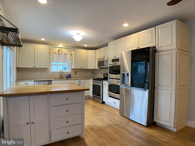 kitchen with white cabinetry, wood counters, stainless steel appliances, and light hardwood / wood-style floors