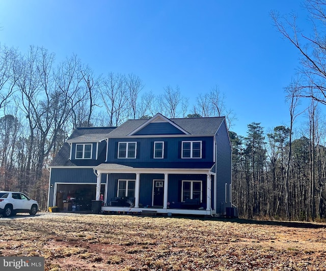 view of front of home with a garage, cooling unit, and covered porch