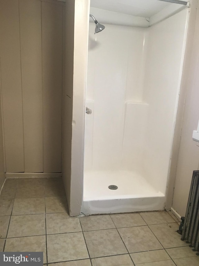 bathroom with tile patterned flooring, radiator, and walk in shower