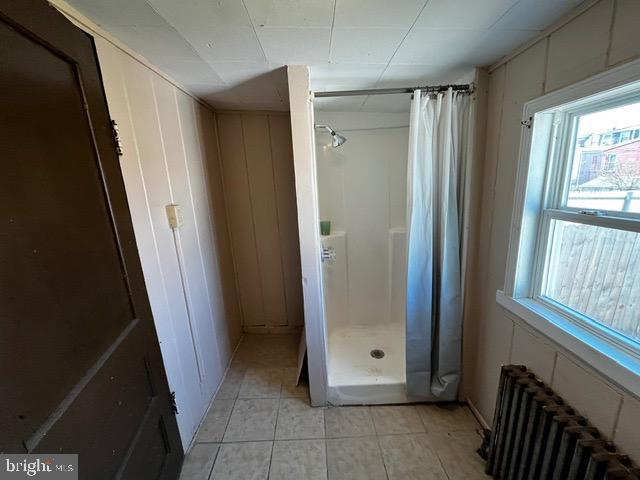 bathroom featuring tile patterned flooring, radiator, and curtained shower