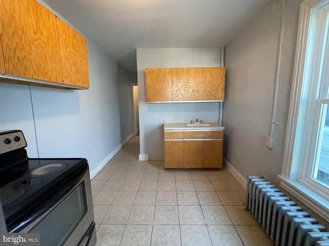 kitchen with stainless steel electric range oven, radiator, sink, and light tile patterned floors