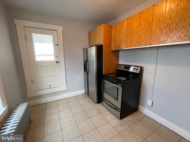 kitchen with appliances with stainless steel finishes, radiator, and light tile patterned floors