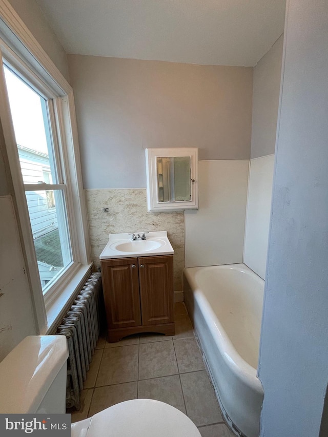 bathroom with radiator heating unit, tile walls, tile patterned flooring, vanity, and toilet