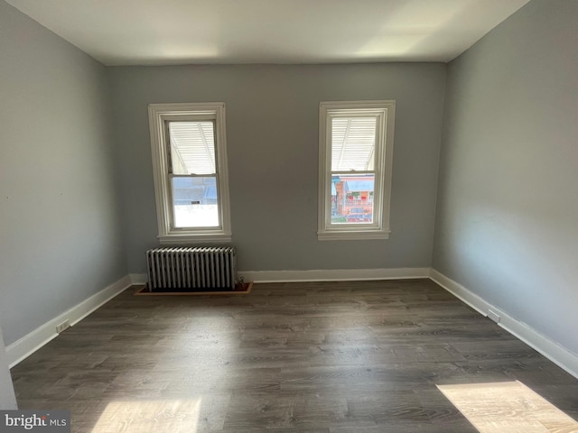 spare room featuring dark hardwood / wood-style flooring and radiator heating unit