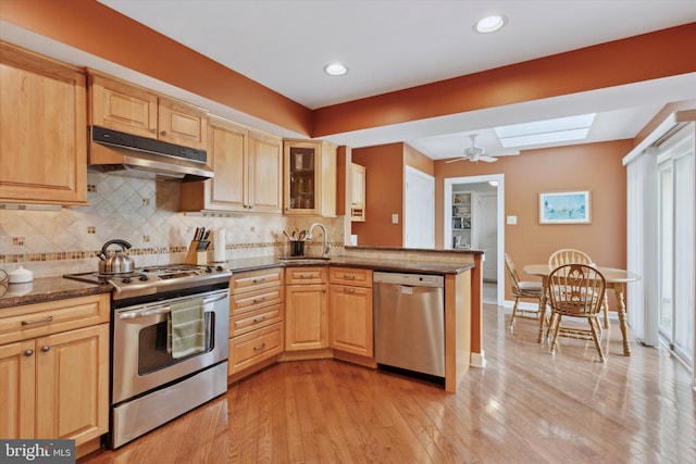 kitchen with light brown cabinetry, sink, a skylight, and stainless steel appliances