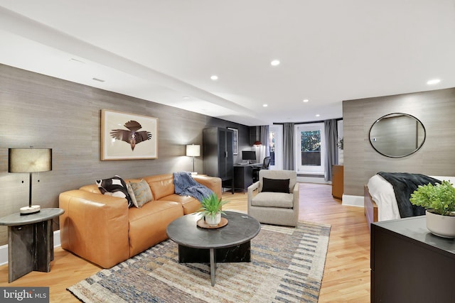 living room featuring an accent wall, recessed lighting, light wood-style flooring, and baseboards