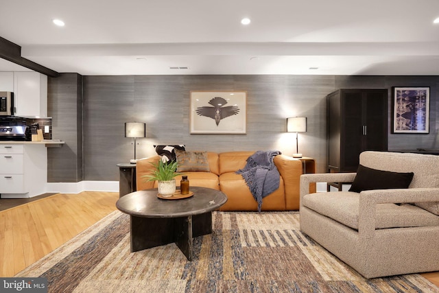 living room featuring recessed lighting, visible vents, baseboards, light wood finished floors, and beamed ceiling