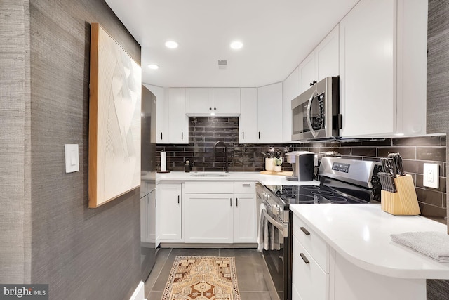 kitchen featuring light countertops, appliances with stainless steel finishes, backsplash, and a sink