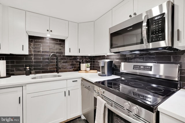 kitchen featuring appliances with stainless steel finishes, white cabinetry, a sink, and tasteful backsplash