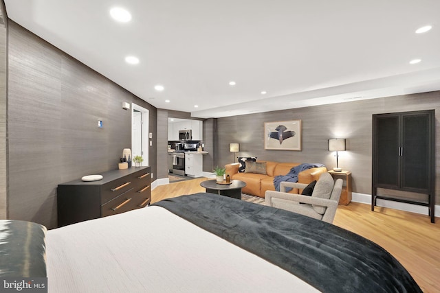 bedroom with baseboards, an accent wall, light wood-type flooring, and recessed lighting