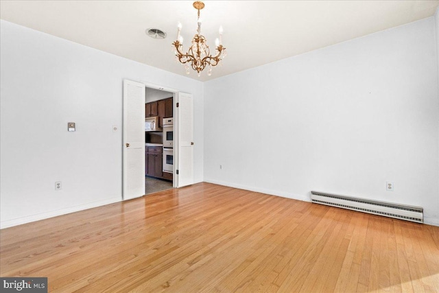 empty room with visible vents, baseboards, a baseboard radiator, wood finished floors, and a notable chandelier