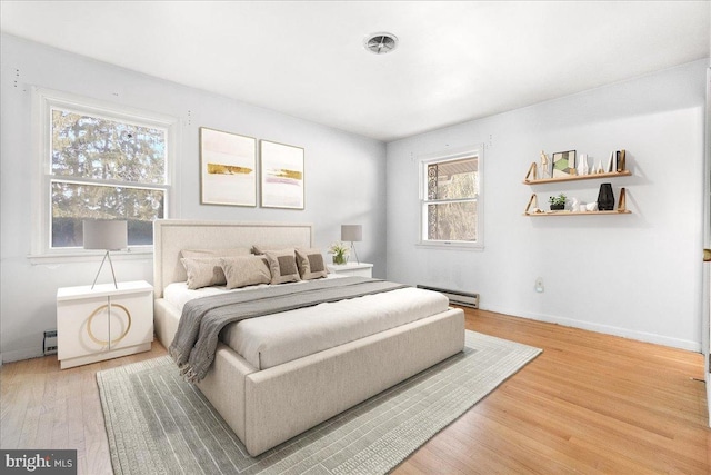 bedroom with baseboards, baseboard heating, and wood finished floors