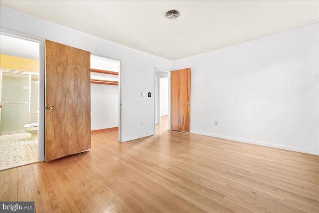 unfurnished bedroom with visible vents, baseboards, light wood-style floors, a closet, and a walk in closet