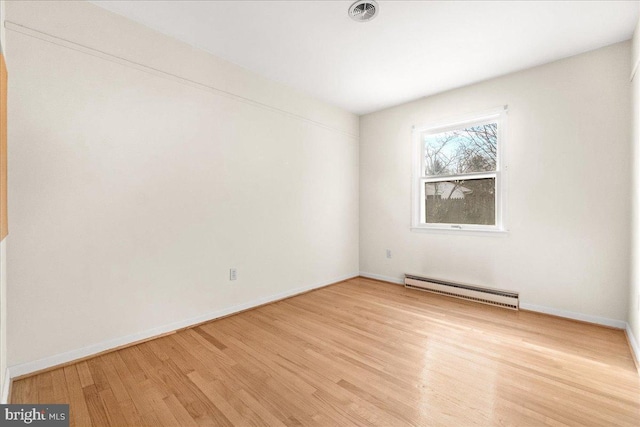 unfurnished room with a baseboard heating unit, light wood-type flooring, visible vents, and baseboards