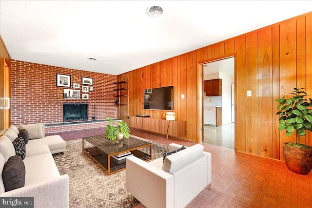 living room with a brick fireplace, visible vents, brick floor, and wood walls