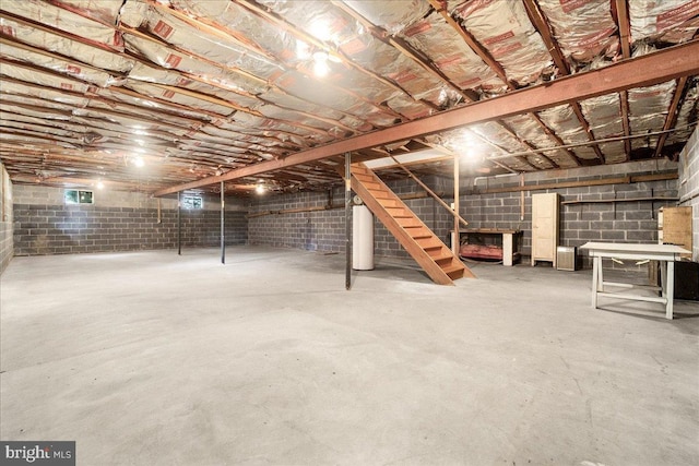 unfinished basement with water heater and stairway