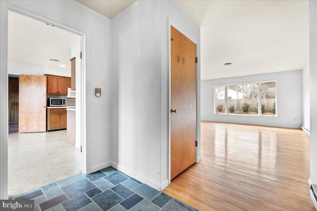 hallway with a baseboard radiator and baseboards