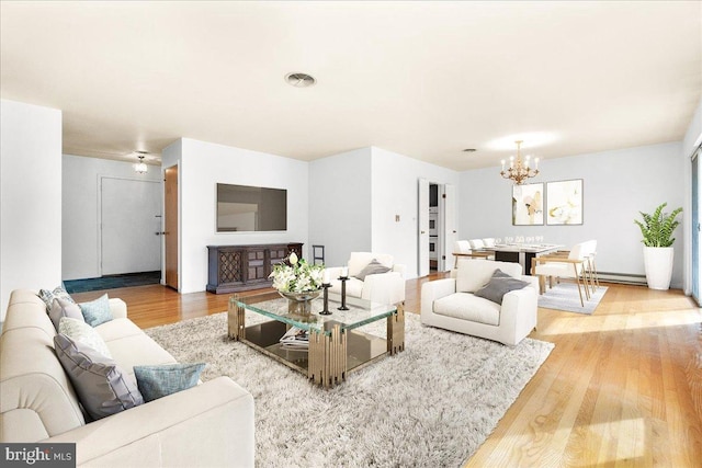 living area with a baseboard radiator, light wood-type flooring, visible vents, and a notable chandelier