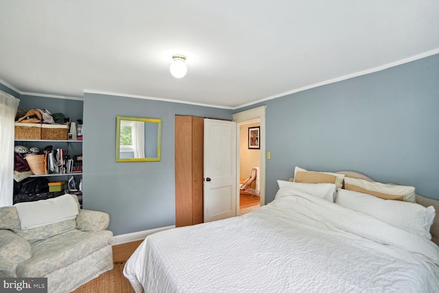 bedroom with crown molding, wood-type flooring, and a closet