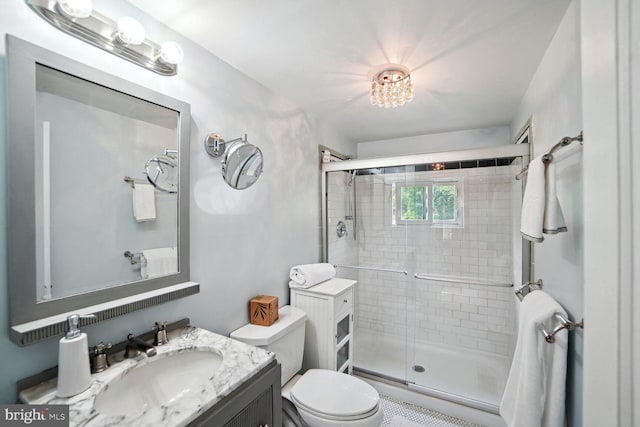 bathroom with vanity, a shower with door, and toilet